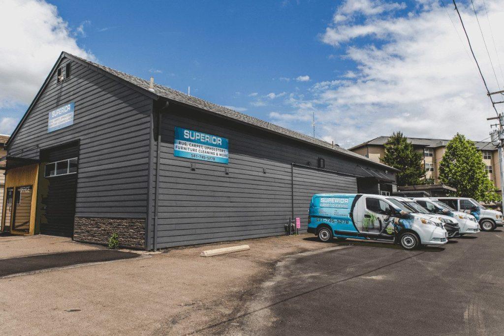 The company's building, its sign over the roller door and the van fleet parked along the yard