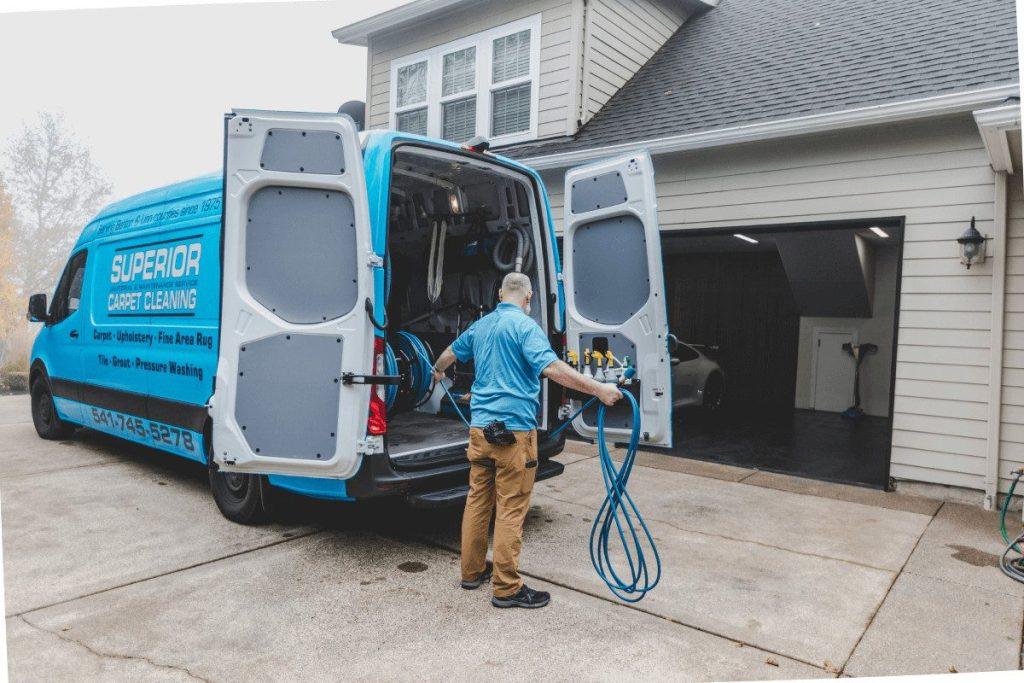 A technician drawing hose from the back of an open van on a driveway