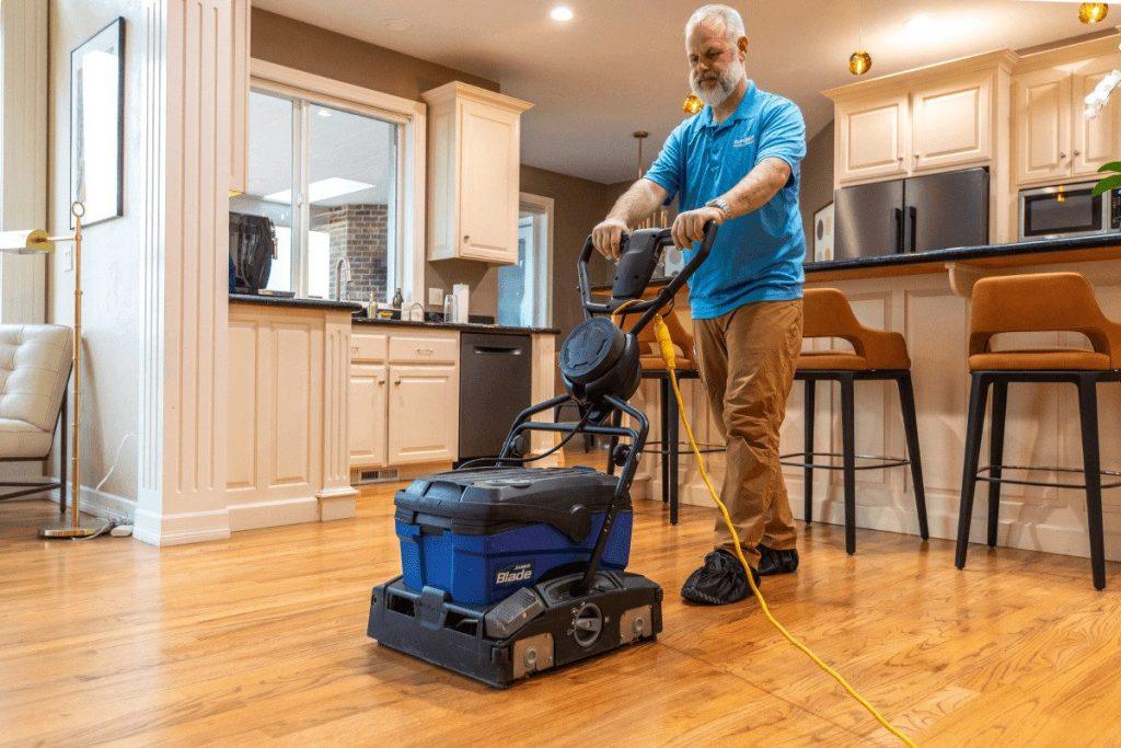 A floor machine being run across a hardwood floor in a kitchen